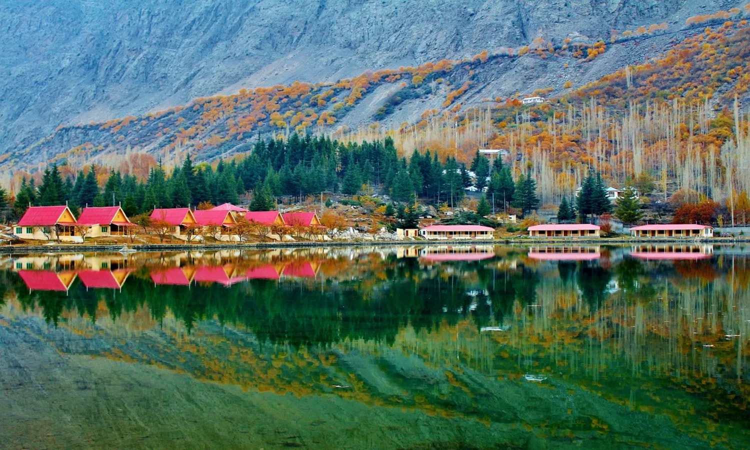 Shangrila (Lower Kachura) Lake with golden reflection of surrounding pines and mountains in Skardu