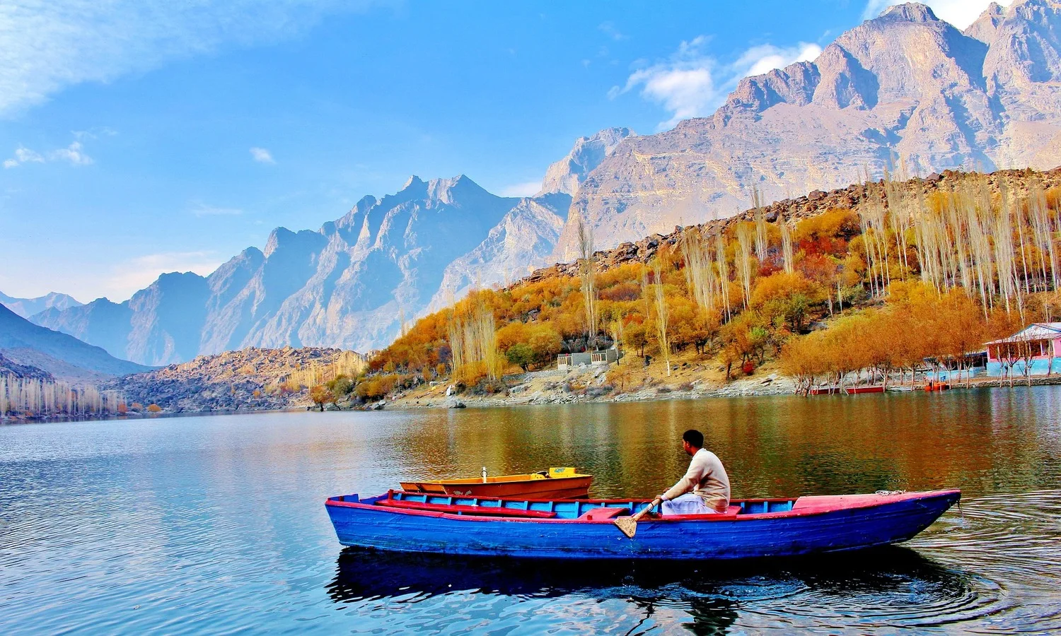 Traveler rowing a traditional wooden boat on Attabad Lake in Hunza Valley, Northern Pakistan